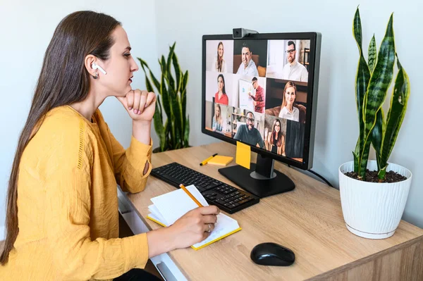 Woman talks with people via video and takes notes — Stock Photo, Image