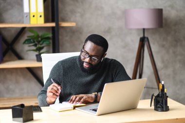 Ofiste dizüstü bilgisayar kullanan Afro-Amerikalı bir adam.