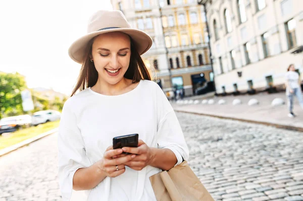 Bella giovane donna in cappello sta chattando al telefono — Foto Stock