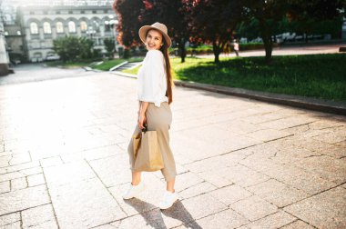 Şehir merkezinde şapkalı hoş bir kadın yürüyor.