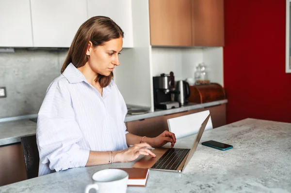 Молодая женщина работает из дома с ноутбуком — стоковое фото