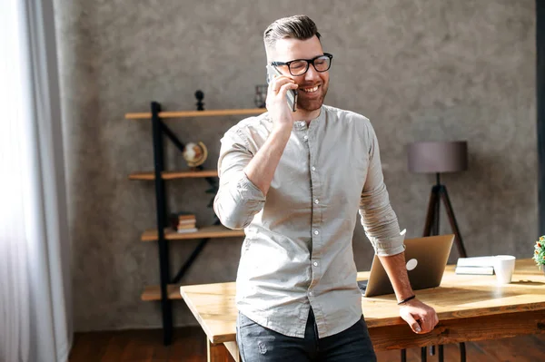 Young man talks on phone in cosy office — Stock Photo, Image