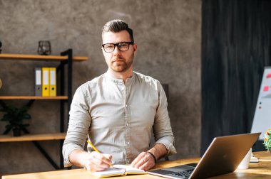 Ciddi bir genç adam dizüstü bilgisayarda çalışıyor.