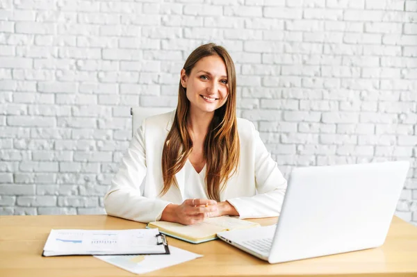 Een jonge blonde vrouw zit aan het bureau — Stockfoto