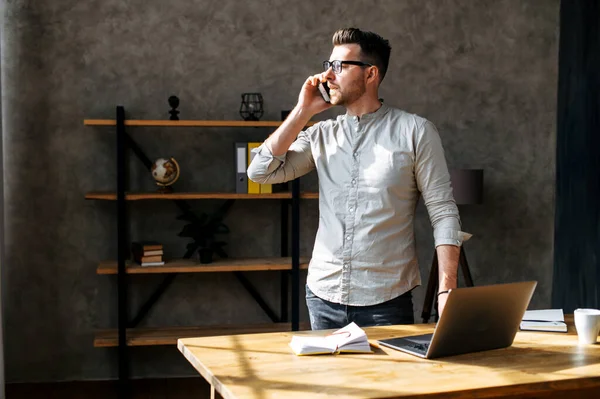 Молодий чоловік розмовляє по телефону в затишному офісі — стокове фото
