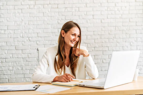 Eine junge blonde Frau arbeitet an einem Laptop — Stockfoto