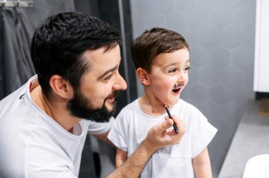 Babam küçük oğlunun yüzüne sakal çiziyor.