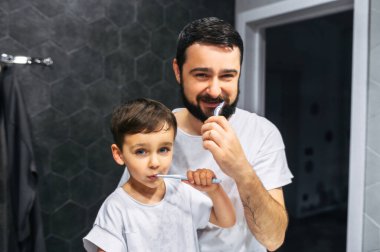 Baba ve bebek dişlerini birlikte fırçalıyorlar.