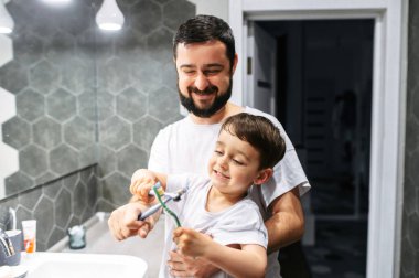 Baba ve bebek dişlerini birlikte fırçalıyorlar.