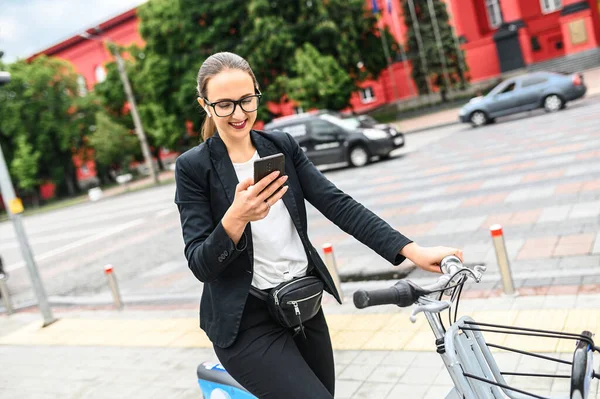 Молода жінка використовує телефон під час їзди на велосипеді — стокове фото