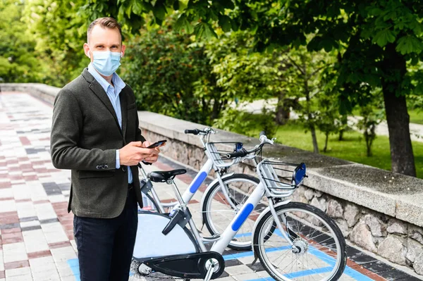Хлопець з медичною маскою одягнений в оренду міський велосипед — стокове фото