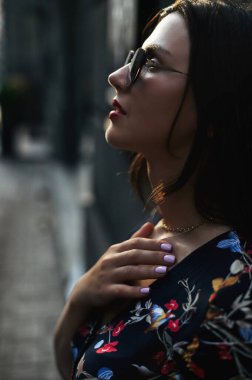 Güneş gözlüklü güzel bir kadın dışarıda poz veriyor.