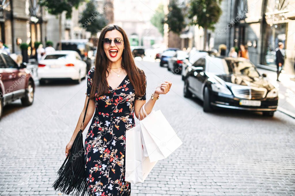 Cheerful girl with shopping bags walks outdoors
