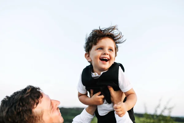 Papa gooit zijn schattige zoon hoog in de lucht — Stockfoto