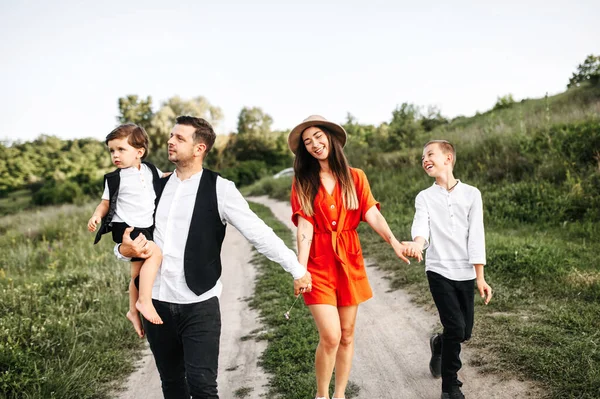 Keluarga bahagia dari empat anggota berjalan melalui lapangan — Stok Foto