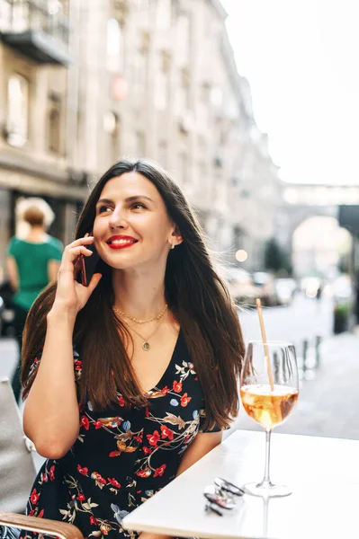 Красива дівчина говорить по телефону в кафе на відкритому повітрі — стокове фото