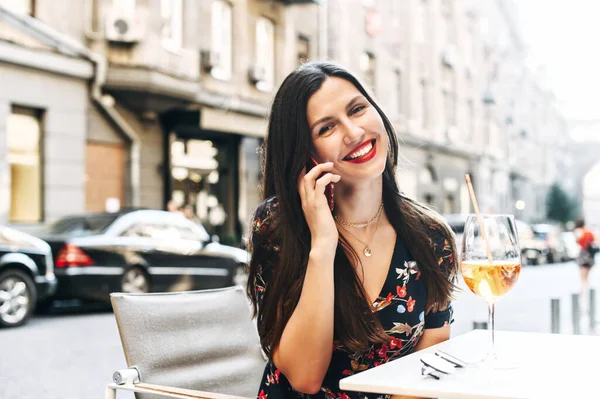 Красива дівчина говорить по телефону в кафе на відкритому повітрі — стокове фото