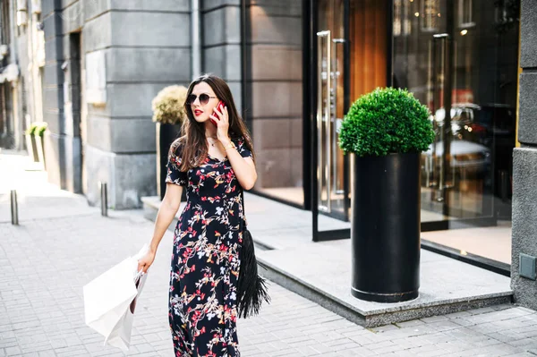 Dívka chodí a mluví po nakupování po telefonu — Stock fotografie