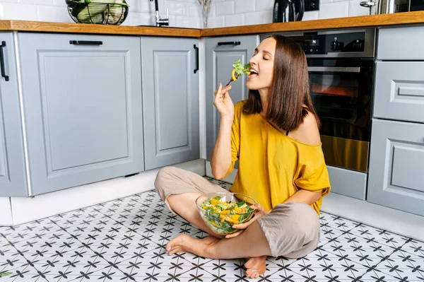 Una donna attraente mangia insalata fresca — Foto Stock