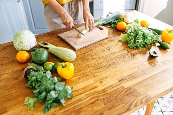 Kvinnliga händer hugger purjolök för en sallad — Stockfoto