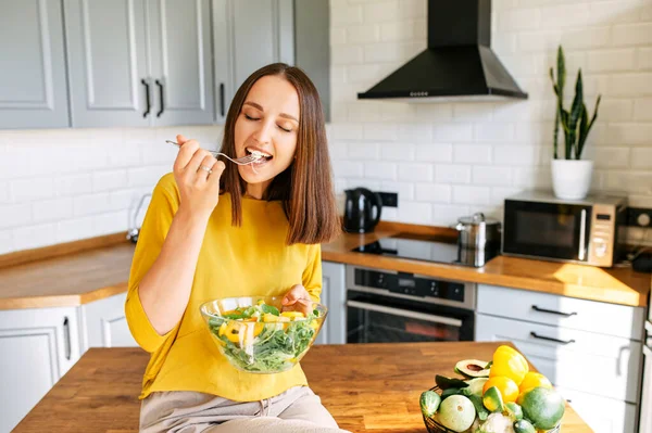 Una donna attraente mangia insalata fresca — Foto Stock