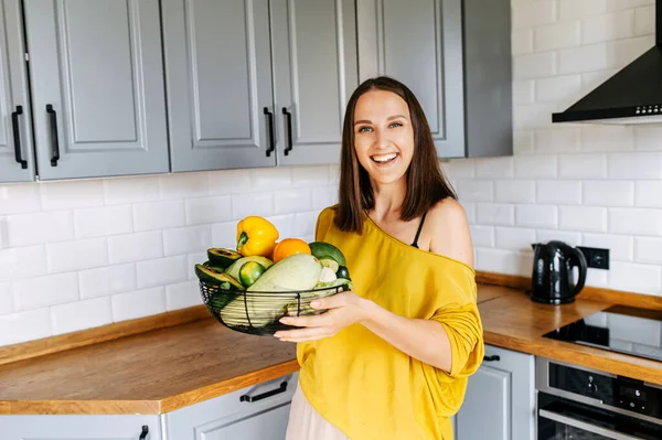 Uma mulher com uma cesta de legumes frescos no interior — Fotografia de Stock