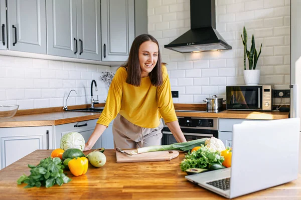 Una donna in cucina e guarda il portatile — Foto Stock