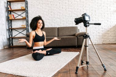 Afro-Amerikalı bir kadın yoga dersleri kaydediyor.