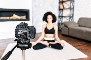 Afro-Amerikalı bir kadın yoga dersleri kaydediyor.