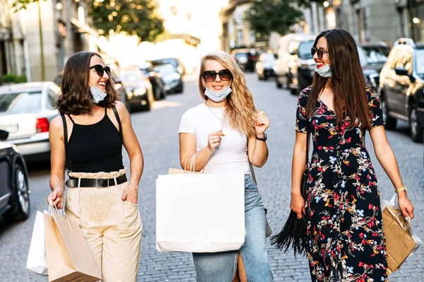 Três amigas em máscaras caminham depois de fazer compras — Fotografia de Stock