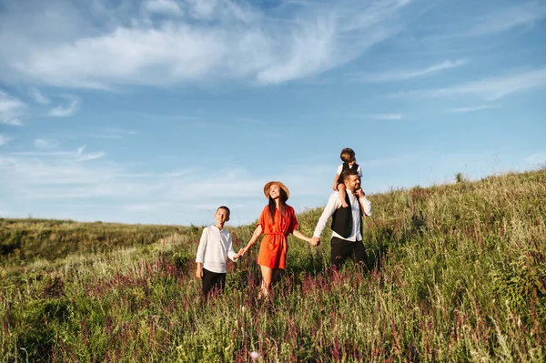 花と一緒に畑を歩く幸せな家族 — ストック写真