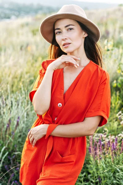 Hermosa mujer en sombrero camina en el campo de flores — Foto de Stock