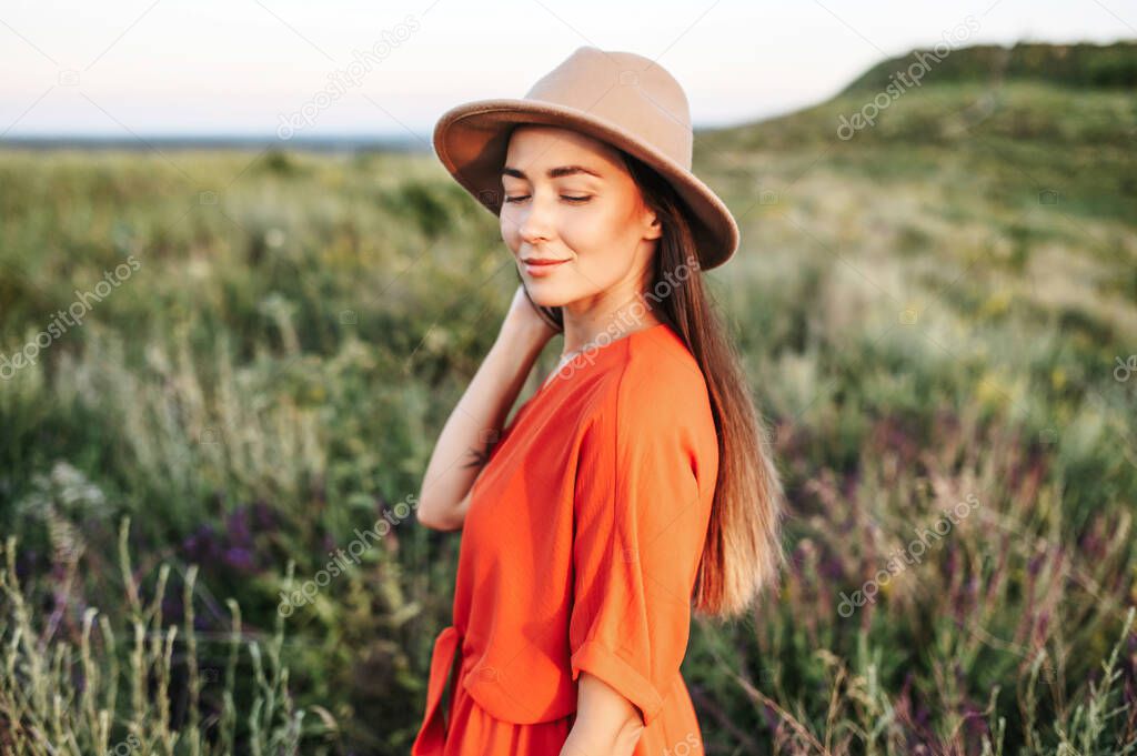 Beautiful woman in hat walks in the flower field