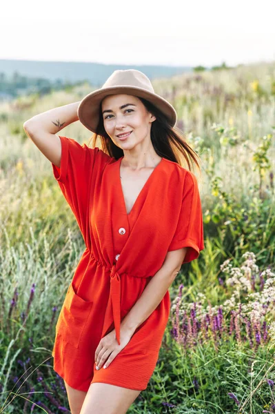 Belle femme en chapeau marche dans le champ de fleurs — Photo