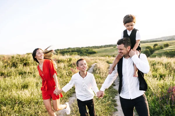 Heureuse famille marchant dans le champ de fleurs — Photo