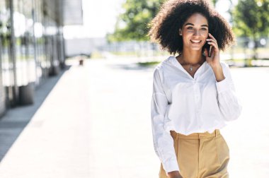 Bir kadın dışarıda telefonla konuşuyor.