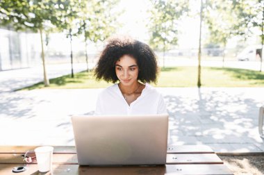 Dışarıda çalışmak için dizüstü bilgisayar kullanan bir kadın.