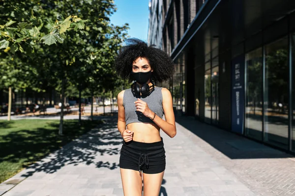 Una donna in maschera medica corre all'aperto — Foto Stock