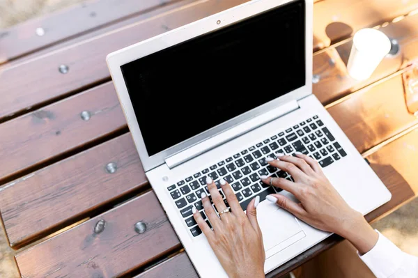 Женские руки на клавиатуре ноутбука на улице — стоковое фото