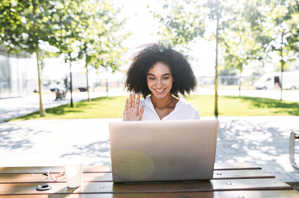 Женщина, использующая ноутбук для видеозвонков на открытом воздухе