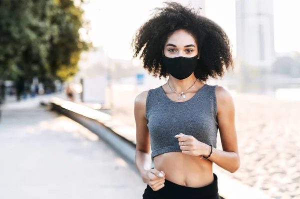 Afro-americano ragazza in maschera è jogging all'aperto — Foto Stock