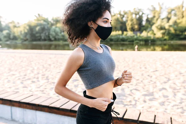 Afro-americano ragazza in maschera è jogging all'aperto — Foto Stock