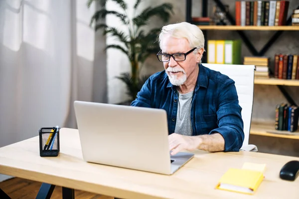 L'uomo più anziano sta usando il computer portatile per lavorare in casa — Foto Stock