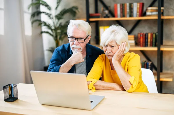 Infeliz pareja de ancianos mira a la pantalla del ordenador portátil —  Fotos de Stock