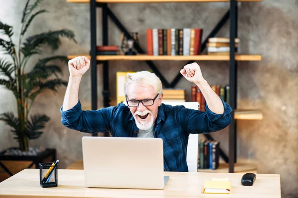 Yaşlı adam içeride çalışmak için dizüstü bilgisayar kullanıyor.