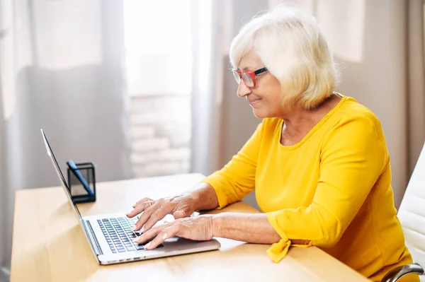 Старшая женщина использует ноутбук для работы в помещении — стоковое фото
