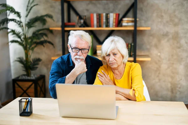 Нещаслива старша пара дивиться на екран ноутбука — стокове фото