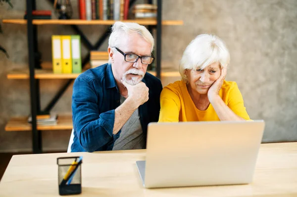 Нещаслива старша пара дивиться на екран ноутбука — стокове фото