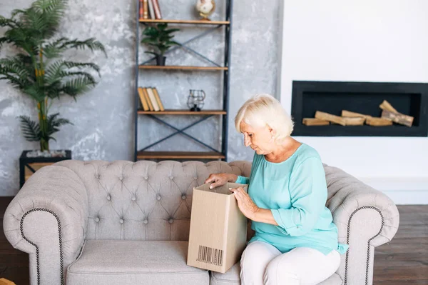 Mujer mayor está desempacando una caja de cartón — Foto de Stock