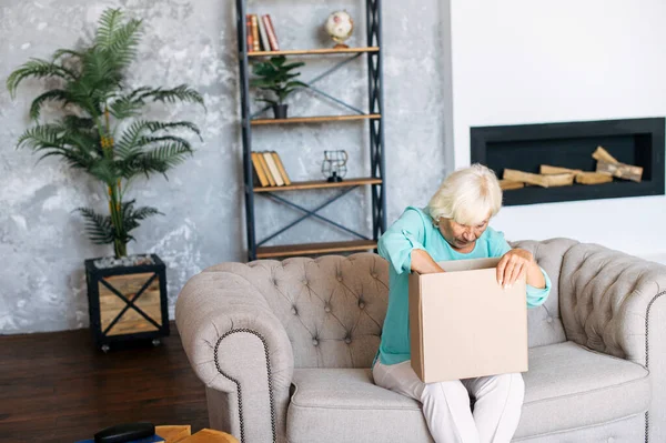 Mujer mayor está desempacando una caja de cartón — Foto de Stock